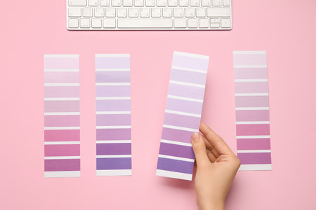 Female hands with violet palette samples and keyboard on pink background. Top viewの写真素材