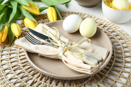 Stylish table setting for Easter celebration with tulip flowers on white grunge background, closeup
