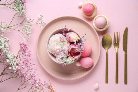 Stylish table setting for Easter celebration with different flowers on pink backgroundの写真素材