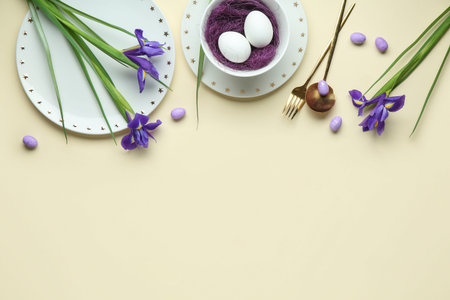 Stylish table setting for Easter celebration with iris flowers on beige background
