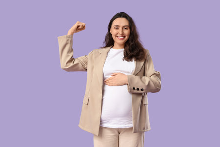 Young pregnant woman showing muscles on lilac background