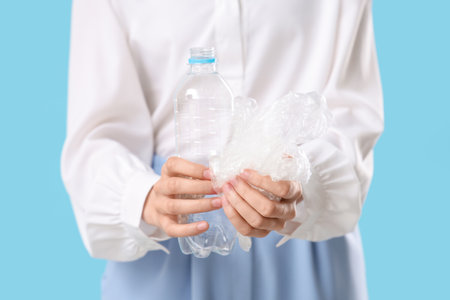 Woman with plastic bottle and bag on blue background, closeupの写真素材