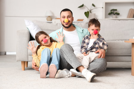 Happy father and his little children with clown noses having fun at home. April fool's day prankの写真素材