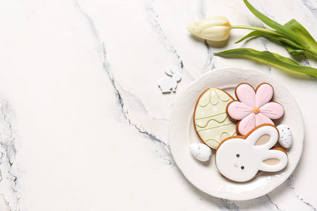 Composition with flower, eggs and different Easter cookies on plate on marble background