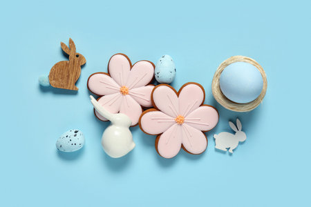 Composition with eggs, decorative bunnies and Easter cookies in shape of flowers on blue background