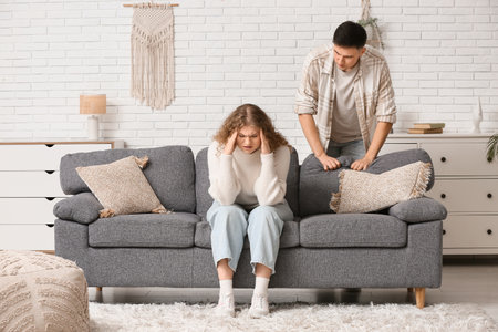 Angry young couple quarreling on sofa at homeの写真素材