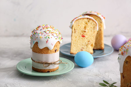 Plates with sweet Easter cakes and painted eggs on gray table