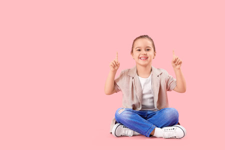 Cute little girl pointing at something on pink backgroundの写真素材