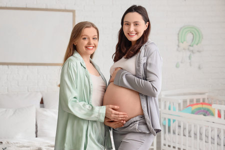 Young pregnant lesbian couple in bedroomの写真素材