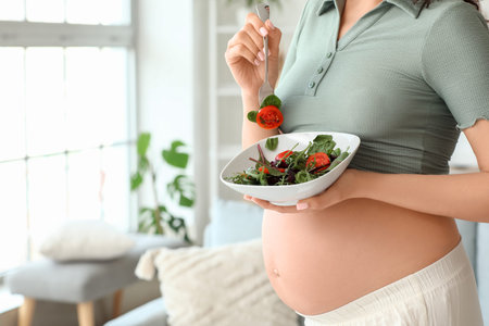 Young pregnant woman with vegetable salad at home, closeup