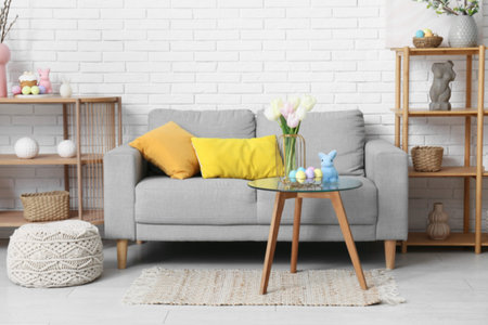 Interior of festive living room with stylish gray sofa, glass coffee table and Easter decorations