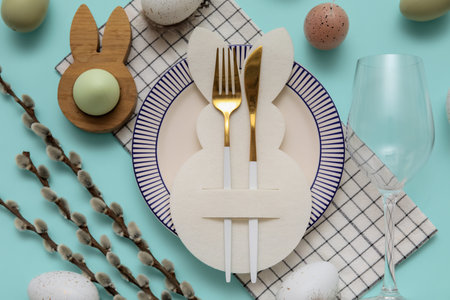 Beautiful table setting with Easter eggs and willow branches on blue background