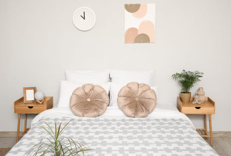 Interior of light bedroom with bedside tables, big bed and pillows