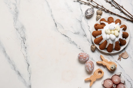 Plate of sweet Easter bread with eggs, wooden rabbits and willow branches on white background