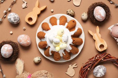Plate of sweet Easter bread with eggs, wooden rabbits and willow branches on brown background