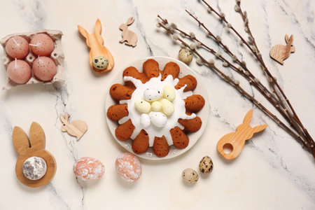 Plate of sweet Easter bread with eggs, wooden rabbits and willow branches on white background