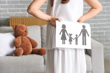 Cute girl with paper family figure at home, back view. Adoption conceptの写真素材