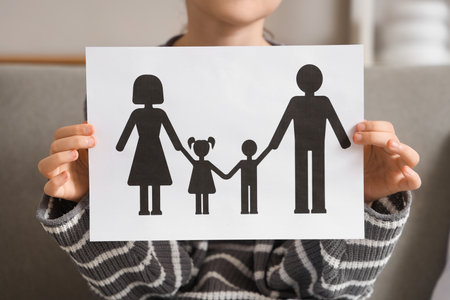 Girl holding paper family figure at home, closeup. Adoption conceptの写真素材
