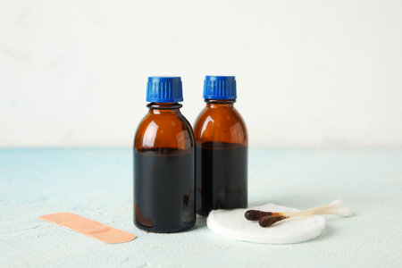 Bottles with iodine, cotton pads, swabs and medical plaster on light blue tableの写真素材