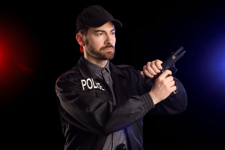 Male police officer with gun against flashing siren lights on black background