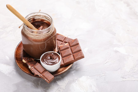 Plate with bowl and jar of chocolate spread on grunge background