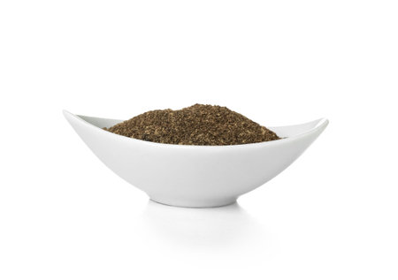 Bowl of black pepper powder on white backgroundの写真素材