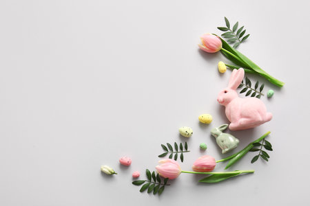 Frame made of Easter eggs, green leaves, tulip flowers and decor on gray backgroundの写真素材