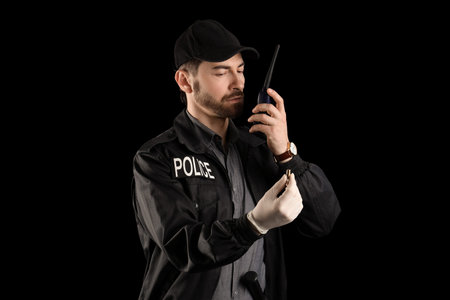 Male police officer with radio transmitter and bullet on black backgroundの写真素材
