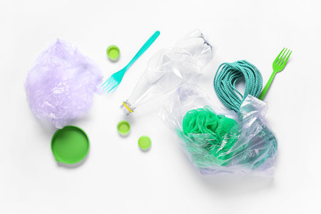 Plastic crumpled bottle with bags, different caps, rope and sponge on white background