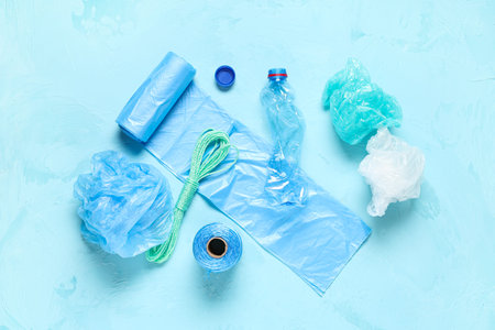 Garbage bags with crumpled plastic bottle, cap and rope on blue grunge background
