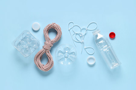 Rope with plastic bottle, container, cable ties and caps on blue background