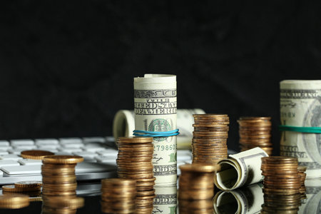 Stacks of coins and dollar banknotes on black background, closeup. Wealth conceptの写真素材