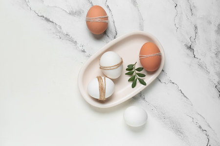 Composition with white tray, Easter eggs and green leaf on marble backgroundの写真素材
