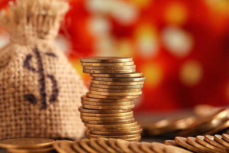 Stacks of coins and money bag on table against blurred lights. Wealth conceptの写真素材