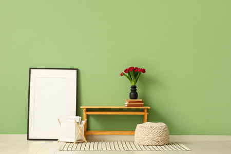 Wooden bench with beautiful tulip flowers, frame and books near green wallの写真素材