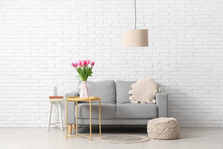 Interior of stylish living room with gray sofa and beautiful tulip flowers on coffee table