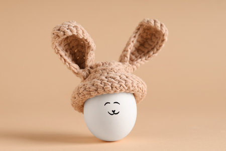 Creative Easter egg with drawn face in bunny ears on color backgroundの写真素材