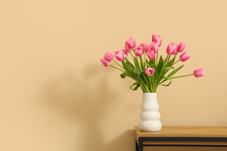 Vase with bouquet of beautiful tulip flowers on bench near beige wall, closeupの写真素材