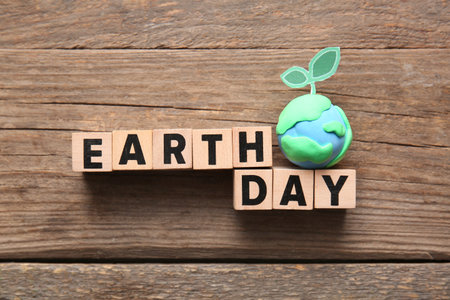 Text EARTH DAY with plasticine planet and sprout on wooden background
