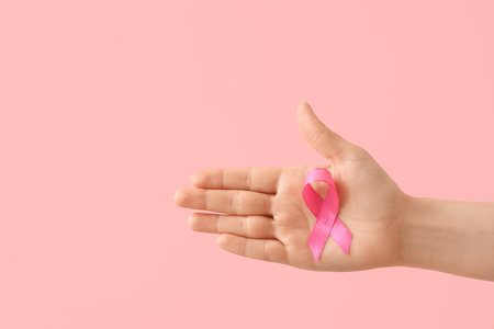 Female hand with pink ribbon on color background. Cancer awareness conceptの写真素材