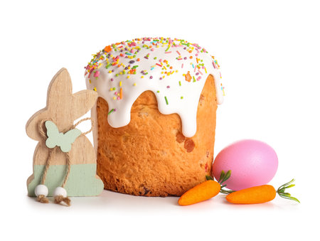 Sweet Easter cake with painted egg, mini carrots and wooden bunny on white backgroundの写真素材
