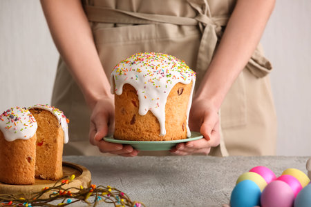 Woman with sweet Easter cakes and painted eggs on white background, closeup