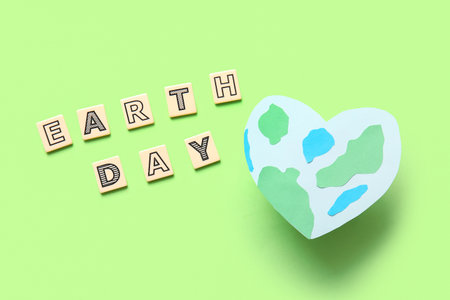 Planet Earth in shape of heart and words EARTH DAY on green background
