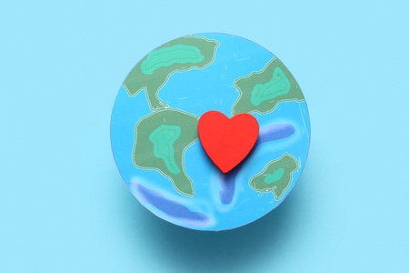 Paper planet Earth with heart on blue background. World Earth Day celebration