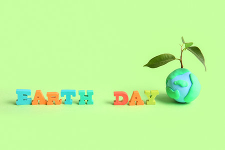Planet Earth with plant and words EARTH DAY on green background. World Earth Day celebrationの写真素材