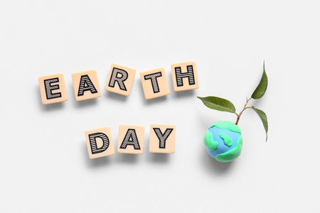 Planet Earth with plant and words EARTH DAY on white background. World Earth Day celebration