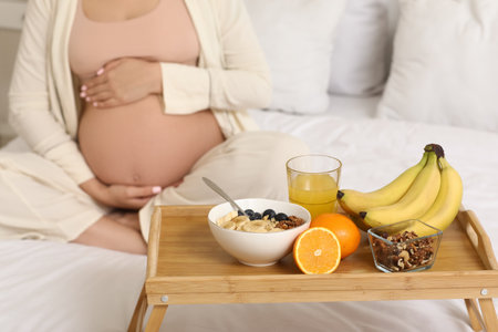 Tray with tasty breakfast against pregnant woman in bedroom, closeupの写真素材