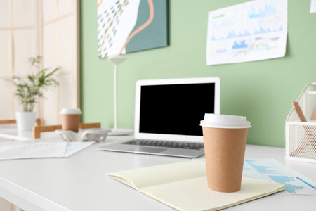 Cup of coffee with notebook on table in office, closeupの写真素材