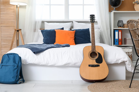 Interior of teenager's room with bed and guitarの写真素材