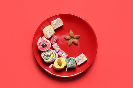 Plate of tasty Eastern sweets and almonds on red background. Ramadan celebrationの写真素材